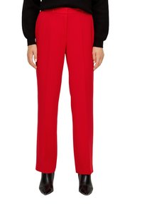 Czerwone dopasowane spodnie z prostymi nogawkami, z płaskim przodem i dwiema bocznymi kieszeniami, zestawione z czarnymi botkami na obcasie.