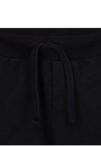 I pantaloni della tuta neri presentano un cinturino elastico in vita con un cordino per la regolazione. Il materiale sembra morbido con una consistenza liscia.