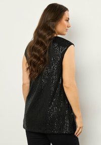 Top nero senza maniche decorato con paillettes, caratterizzato da una vestibilità ampia e un orlo dritto, con una texture liscia e una finitura lucida.