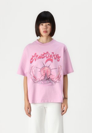 Camiseta de algodón rosa de corte oversized que presenta un diseño gráfico de un sol y un volcán. Mangas cortas y cuello redondo, con tejido texturizado.