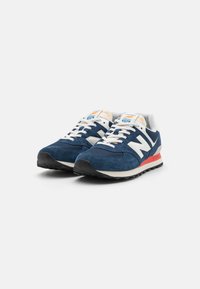 Navy blue suede and mesh running shoes with white accents, featuring cream laces and a red outsole. New Balance logo on the side.