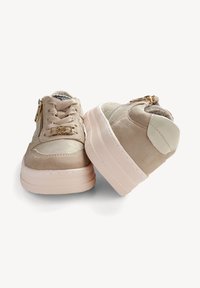 Beige Wildleder-Sneaker mit pinkfarbenen Gummisohlen, Schnürung auf der Vorderseite, dekorativem Reißverschluss und abgerundeter Zehenpartie. Glatte Akzente nahe der Ferse.