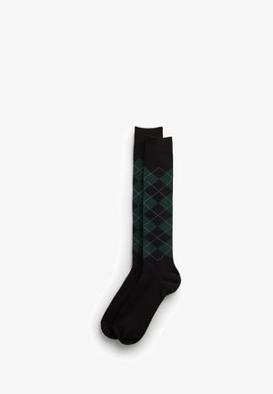 Par de calcetines negros hasta la rodilla con patrón de diamantes argyle en verde oscuro y negro en la sección de la pierna.