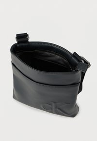 Μαύρο δερμάτινο τσαντάκι χιαστί με φερμουάρ, λεία υφή και ανάγλυφο λογότυπο. Ρυθμιζόμενο λουρί και εξωτερική τσέπη.