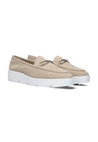 Beige suède instappers met een minimalistisch ontwerp, voorzien van een dikke witte zool en zilveren hardware-accenten op het bovenwerk.