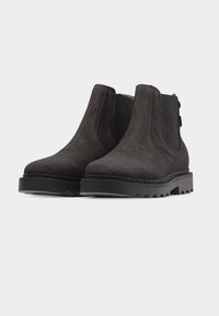 Ζευγάρι μαύρα γκέιτς από σουέντ με παχιά ελαστική σόλα και ελαστικές πλαϊνές επενδύσεις σε λευκό φόντο.