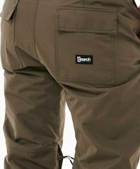 Pantalons cargo pour homme en tissu brun foncé, avec de multiples poches latérales, un patch logo et des zips le long des jambes inférieures pour la ventilation.