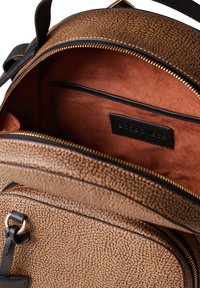 Zaino in pelle marrone con esterno texturizzato, zip dorata e morbido interno beige con tasca con zip e etichetta del marchio.