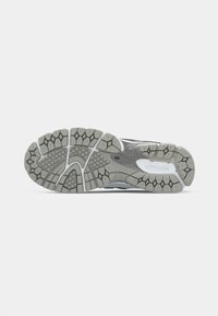 Gray and white sneaker sole with a textured grip pattern, including diamond shapes and flex grooves for traction and flexibility.