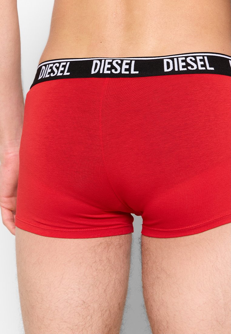 Boxer-briefs en coton rouge avec une ceinture élastique noire portant le logo "DIESEL" en blanc. Le tissu est lisse et ajusté.