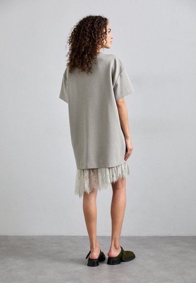 Üks suur hall sviitriga kleit lühikeste varrukatega, millel on pitsist äär, ning see on ühendatud tumeroheliste libisemisjalgade ja paksu kontsaga.