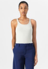 Lichtbeige geribde tanktop met een ronde halslijn, gecombineerd met marineblauwe taillepantalons met zijzakken en een rechte voorkant.