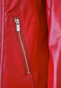 Rote Lederjacke mit einer silbernen Reißverschlusstasche, die eine glatte Textur und gestickte Details entlang der Nähte aufweist.