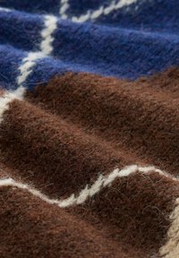 Wollen stof met een zachte textuur, in een kleurenpalet van bruin, blauw en wit, met een golvend patroon en subtiele vezels.