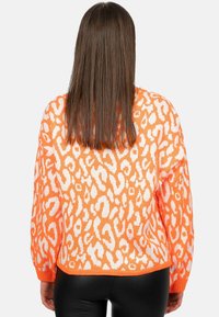 Maglione lavorato a maglia arancione con stampa leopardata bianca, caratterizzato da una vestibilità comoda, maniche lunghe e orlo a coste. Texture morbida e design informale.