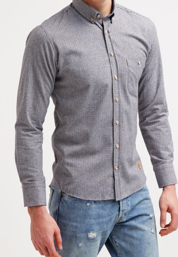 Camicia a bottoni in un motivo a quadretti bianco e nero. Presenta un colletto, maniche lunghe e bottoni in legno. Abbinata a jeans blu strappati.