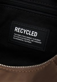 L'étiquette à l'intérieur du sac indique que le produit est mélangé avec des matériaux recyclés pour réduire l'empreinte environnementale.