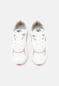 Ζευγάρι λευκά και μπεζ αθλητικά παπούτσια Hi-Tec με κορδόνια, σε άποψη από πάνω πάνω σε απλό ανοιχτό φόντο.