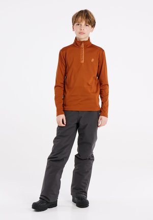 Oranje pullover met lange mouwen, een halflange rits en logodetail, gecombineerd met donkergrijze broek en zwarte schoenen. Eenvoudig, functioneel ontwerp.