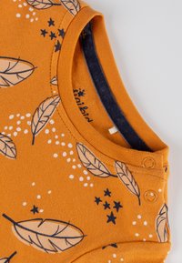 Oranges Baumwollbodysuit mit navyblauen Blatt- und Sternmustern, runder Halsauschnitt und zwei Druckknöpfen an der Schulter für ein einfaches Ankleiden.