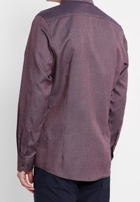 Camicia a maniche lunghe in borgogna scuro con un motivo a spina di pesce testurizzato. Caratterizzata da un colletto classico e polsini con bottoni. Vestibilità su misura.