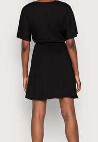Černé šaty s krátkým rukávem, volného střihu, elastickým pasem a rozšířenou sukní. Vyrobeno z měkké látky s hladkou texturou a minimálním zdobením.
