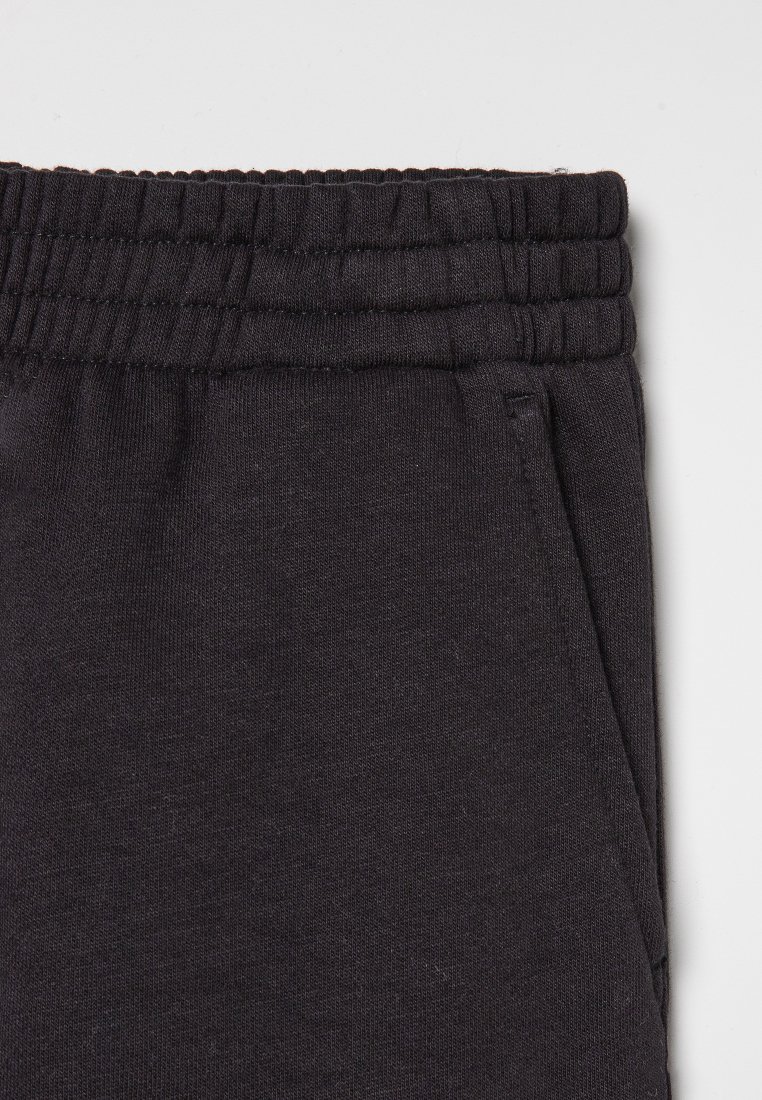 Pantalons de survêtement en tissu texturé avec taille élastique noire et poches latérales.