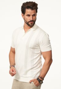 Kurzarmpolohemd in Creme mit strukturierten vertikalen Streifen, aus weichem Baumwollmischgewebe gefertigt, mit einer Knopfleiste mit zwei Knöpfen und geripptem Kragen.
