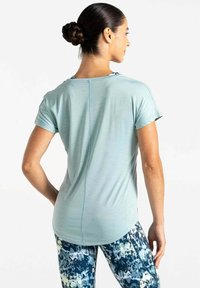 Camiseta atlética de color azul claro con mangas cortas y dobladillo redondeado, combinada con leggings de estampado azul y blanco. Tejido suave y texturizado.