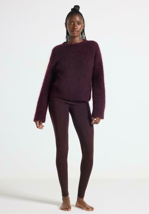 Burgundy fluffig tröja med långa ärmar, kombinerad med mörk burgundy leggings. Tröjan har en avslappnad passform och ribbad fålldetalj.