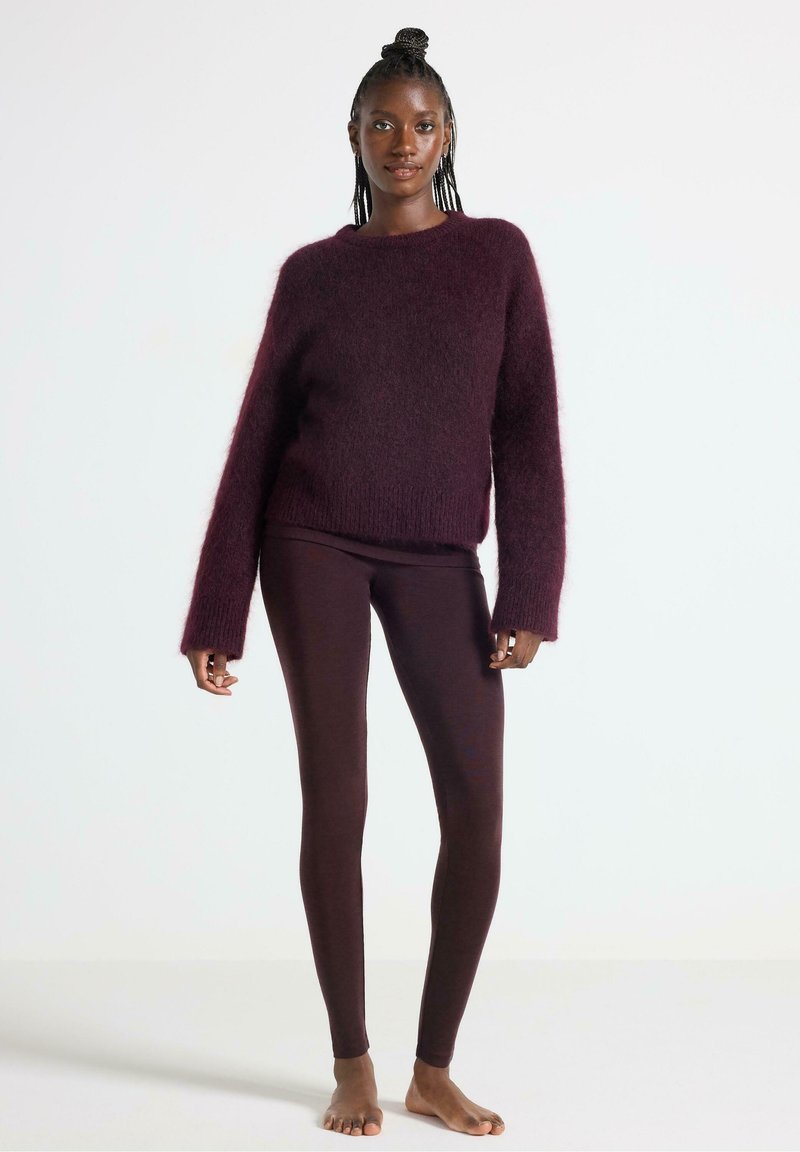 Burgundy fluffig tröja med långa ärmar, kombinerad med mörk burgundy leggings. Tröjan har en avslappnad passform och ribbad fålldetalj.