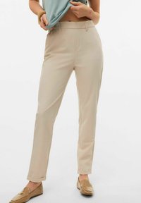 Beige op maat gemaakte broek met een gladde textuur, rechte snit en omgeslagen manchetten, gecombineerd met lichtbruine loafers.