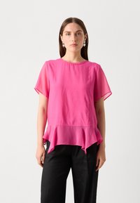 Rosa chiffongblus med korta ärmar och utställd nederkant. Slät textur och lättviktsdesign. Matchad med svarta byxor.