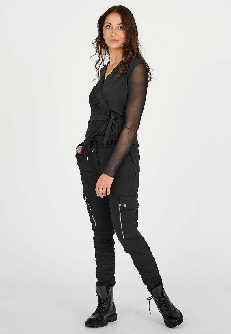 Sort langærmet top med omslag, parret med tapered sorte cargo-bukser med lynlåslommer og sorte kampstøvler.