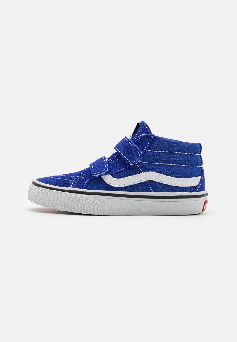 Zapatilla alta de lona azul con acentos blancos, correas de velcro y ribetes negros sobre una suela de goma blanca. Detalle de costura visible.