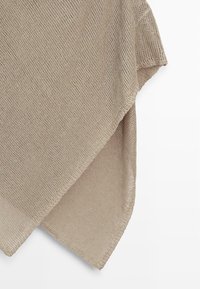 Beżowy dziergany sweter bez rękawów z opuszczonym ramieniem i nierównym dołem, wiszący na białym tle.