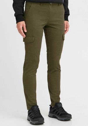 Pantaloni cargo de culoare verde măsliniu, cu tăiere slim, două buzunare cargo și o textură netedă, asortați cu încălțăminte sport neagră.