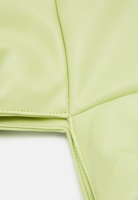 Detailní záběr na světle zelenou polstrovanou kůži s precizním šitím na měkkém, polstrovaném povrchu.