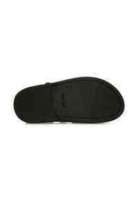 Suela de calzado negra con una superficie texturizada, forma redondeada y un borde elevado. Presenta logotipos en relieve y un contorno suave.
