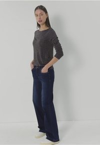 Tummanharmaa pitkähihainen pusero yhdistettynä tummansinisiin leveälahkeisiin farkkuihin. Mallilla on päällään valkoiset tennarit. Silkkinen materiaali, jossa on hienovarainen rakenne ja istuvuus.