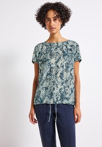 Kurzärmlige Bluse in Grün und Creme mit Schlangenprint-Muster. Sie hat einen gerafften Ausschnitt und einen verstellbaren Kordelzug am Saum.