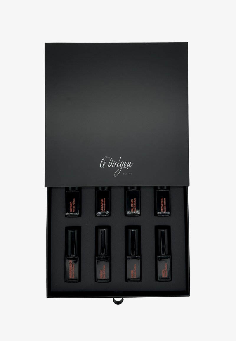 Boîte cadeau noire avec une finition mate lisse, l'intérieur contient huit petits flacons de parfum noirs, étiquettes orange, avec différents noms.