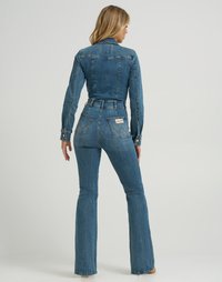 Jumpsuit en denim bleu foncé avec des manches longues et des jambes évasées. Présente des poches arrière, une texture décolorée et une étiquette de marque au dos.