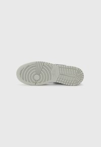 Nike spordijalatsite väline hallist kummist, millel on ringjad ja joonelised mustrid; sisaldab reljeefset logo detaili kandil ning tekstureeritud haardepindu.