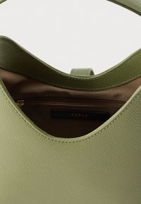 Πράσινη δερμάτινη τσάντα με υφή στην επιφάνεια, με ομαλή, στρογγυλή άνοιξη και εσωτερική τσέπη με φερμουάρ. Επενδεδυμένη με ανοιχτόχρωμο ύφασμα.