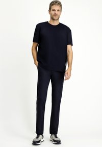 Camiseta de marina con mangas cortas, combinada con pantalones ajustados de marina a juego. El modelo lleva zapatillas gris y negro. Diseño simple y minimalista.