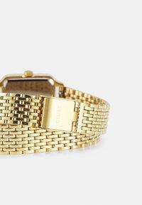 Montre en métal doré avec un bracelet tissé, boîtier rectangulaire et fermoir gravé "CLUSE". Fini lisse et brillant avec un design élégant.