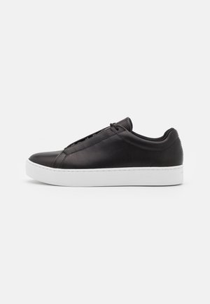 Black leather sneakers with a smooth finish, featuring a low-top design and a thick white rubber sole. Subtle stitching details on the side.