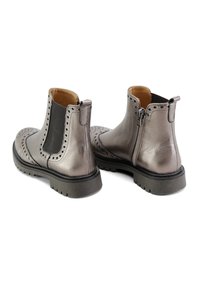 Botines metálico gris con detalles de brogue, paneles laterales elásticos negros, cremallera trasera y suela de goma texturizada. Acabado en cuero liso.