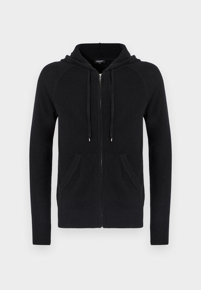 Sweatshirt preto com fecho e bolsos frontais, equipado com cordões, feito de um tecido macio, exibido contra um fundo branco liso.